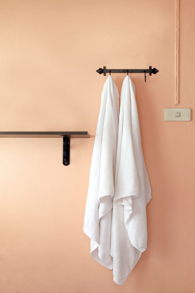 Two white long bath towel hanged on a small towel rack