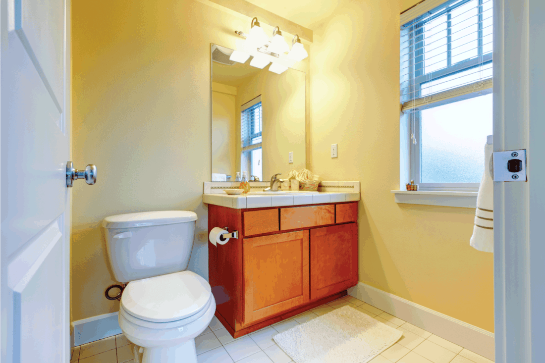 Yellow bright small bathroom with wooden cabinets