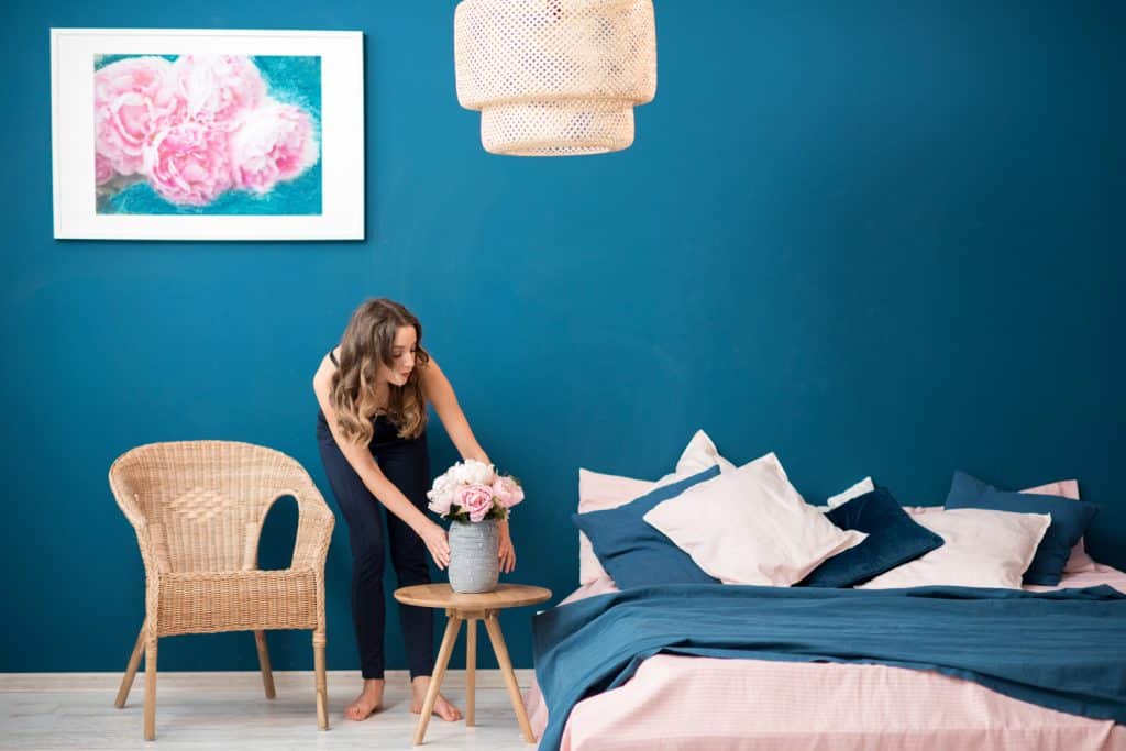 Young woman decorating bedroom with beautiful flowers at home