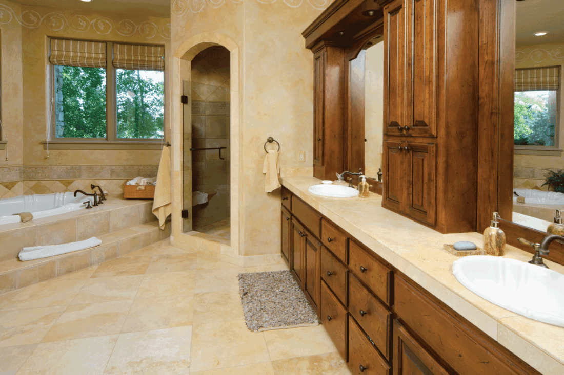elegant-modern-bathroom-has-a-sunken-bathtub.-beige-tiles-and-wooden-cabinets-and-vanity.-What-Color-Bathroom-Cabinets-And-Vanity-Go-With-Beige-Tile