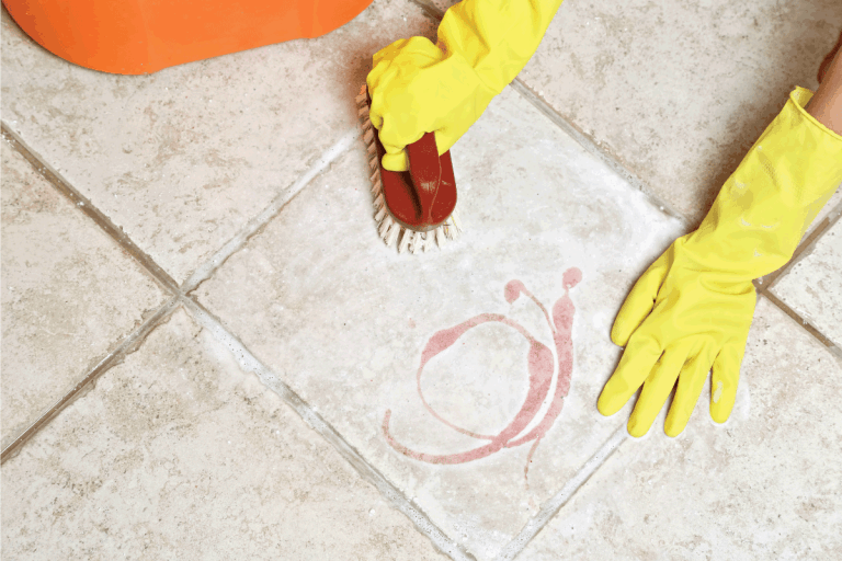 hands with yellow rubber gloves scrubbing the tile floor and grout. Can You Use Bleach To Clean Bathroom Tile Grout