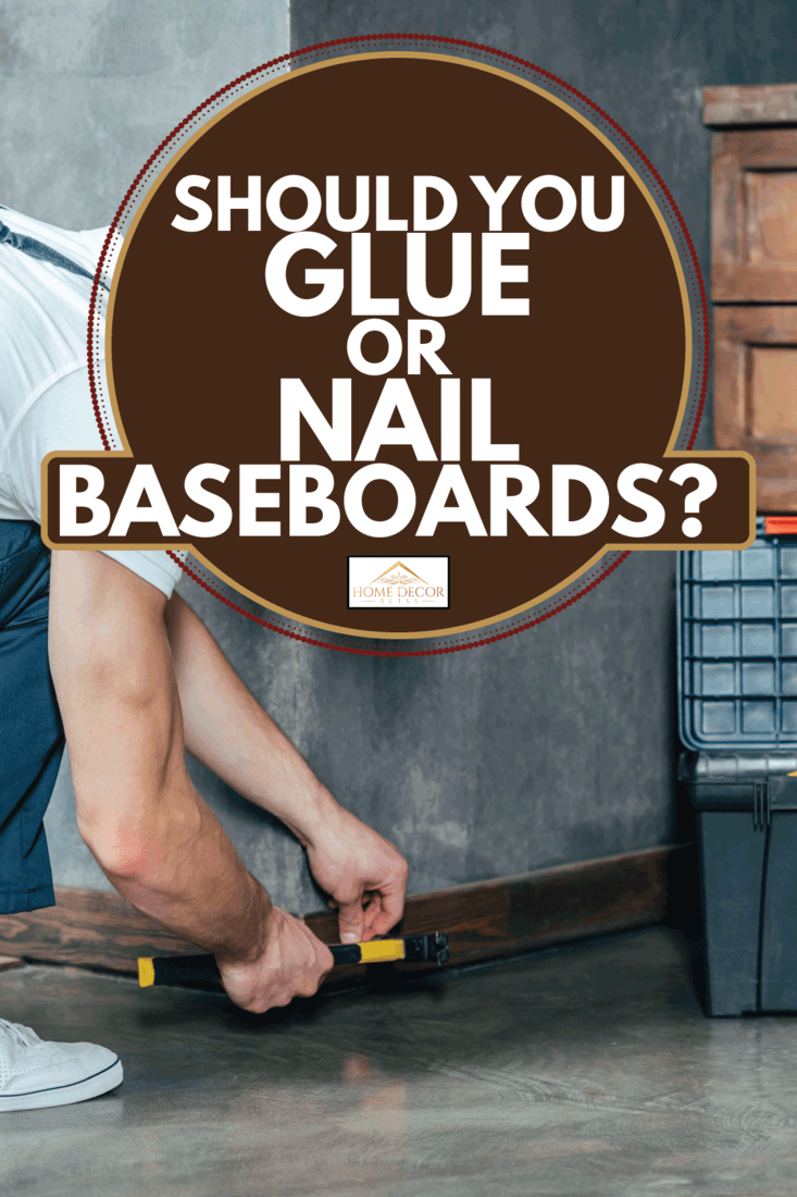 young carpenter hammering nail into baseboard. Should You Glue Or Nail Baseboards