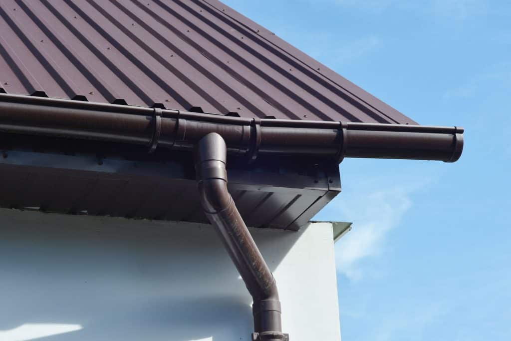 A brown metal roofing, brown painted gutter, and black painted eaves and fascia board