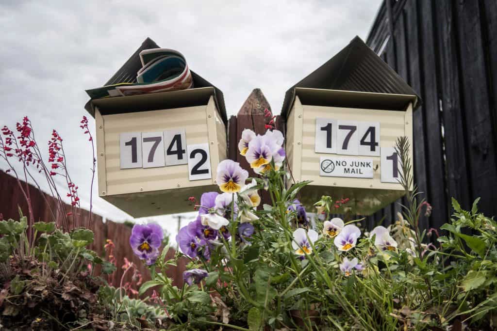 A double mailbox with a small birdhouse type design