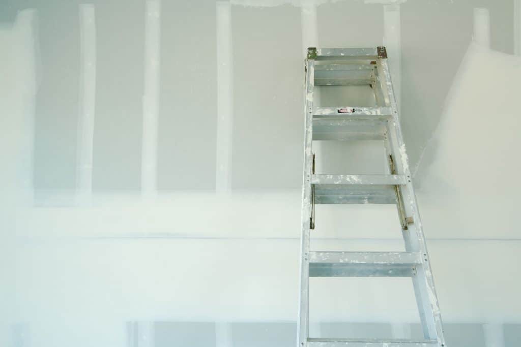 A metal ladder leaning on the drywall