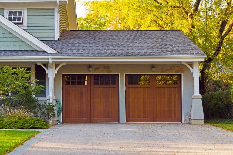 A two wooden garage door with small window and a two storey house, Should A Garage Have Windows?