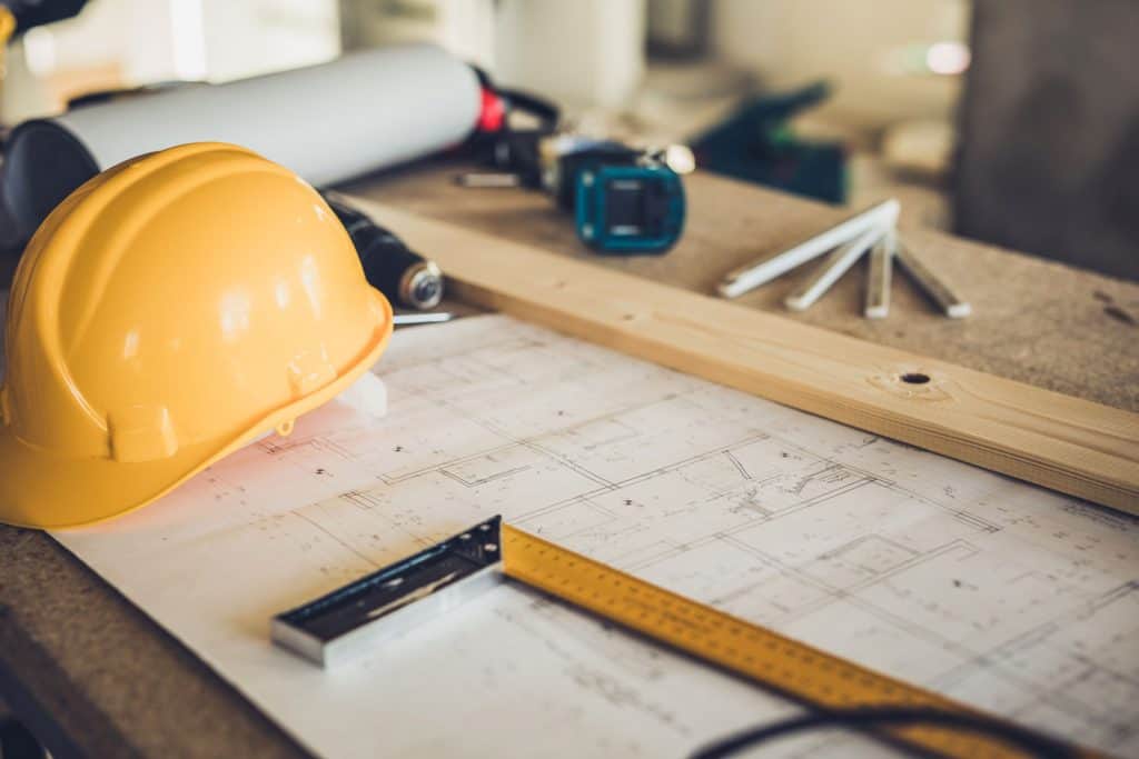 An architectural blueprint with measuring tools and a yellow hard hat