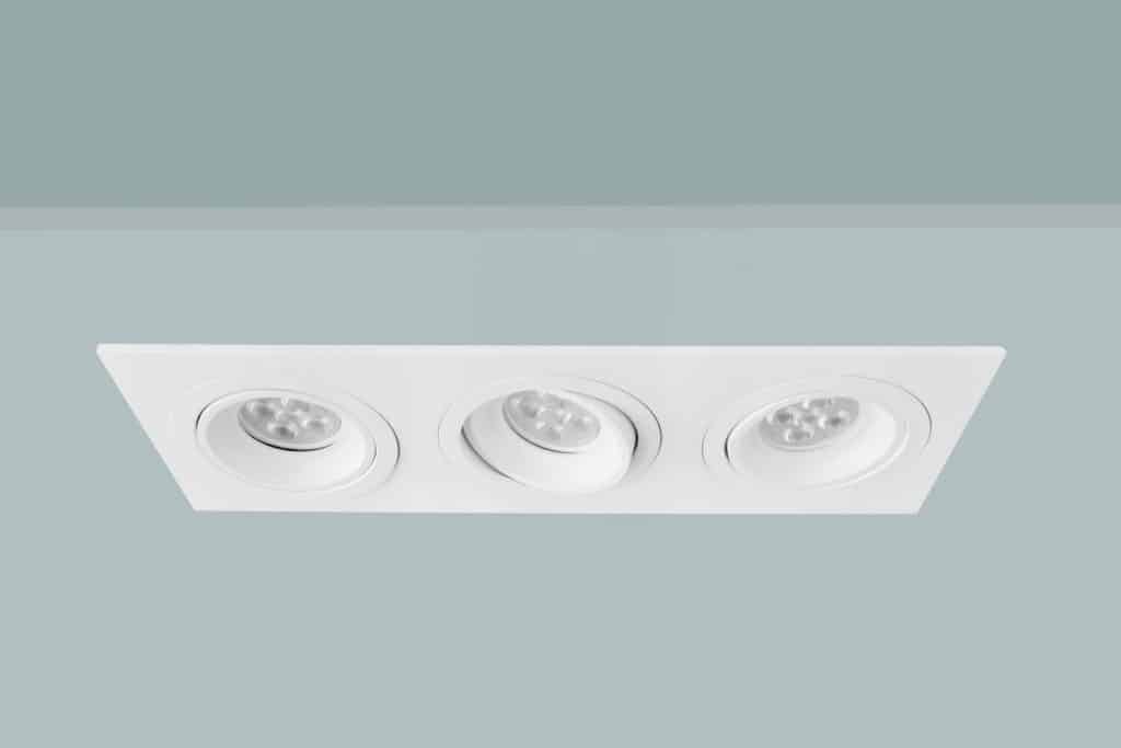 An up close photo of adjustable recessed lighting on a light blue colored ceiling 