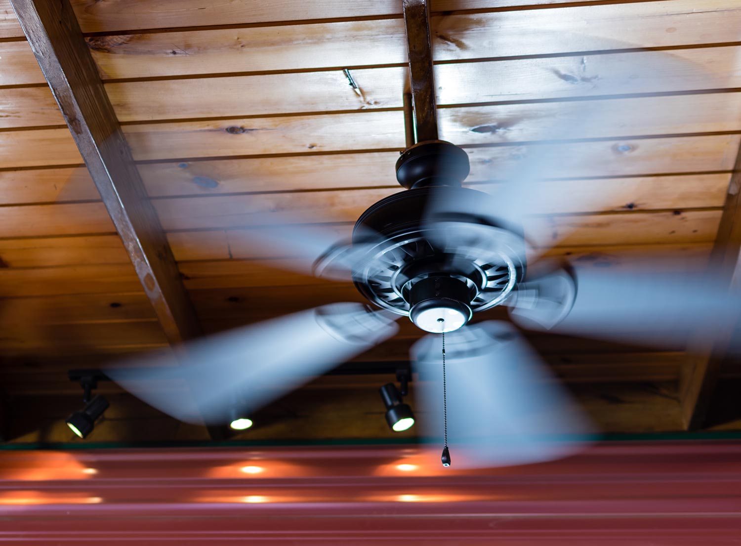 Ceiling fan shows motion blur as its blades spin around
