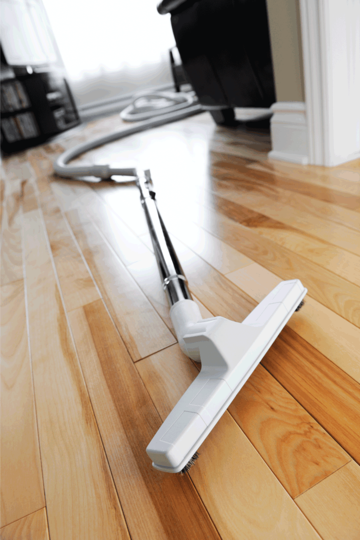 Central vacuum brush and hose on a hard wood floor, inside a home