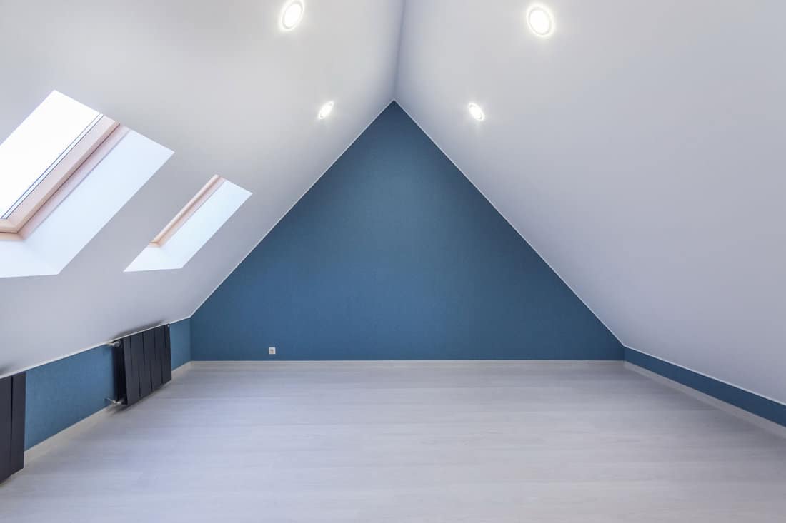 Empty attic room with sloping ceiling and two skylight windows 