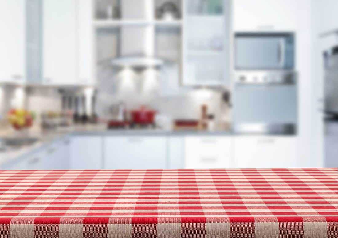 Empty kitchen countertop covered with red and white checkered tablecloth