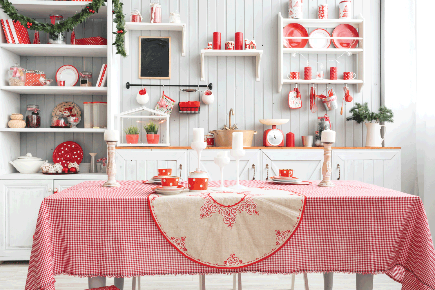 Interior light grey kitchen and red christmas decor. pink tablecloth with light flowy curtains on the windows.