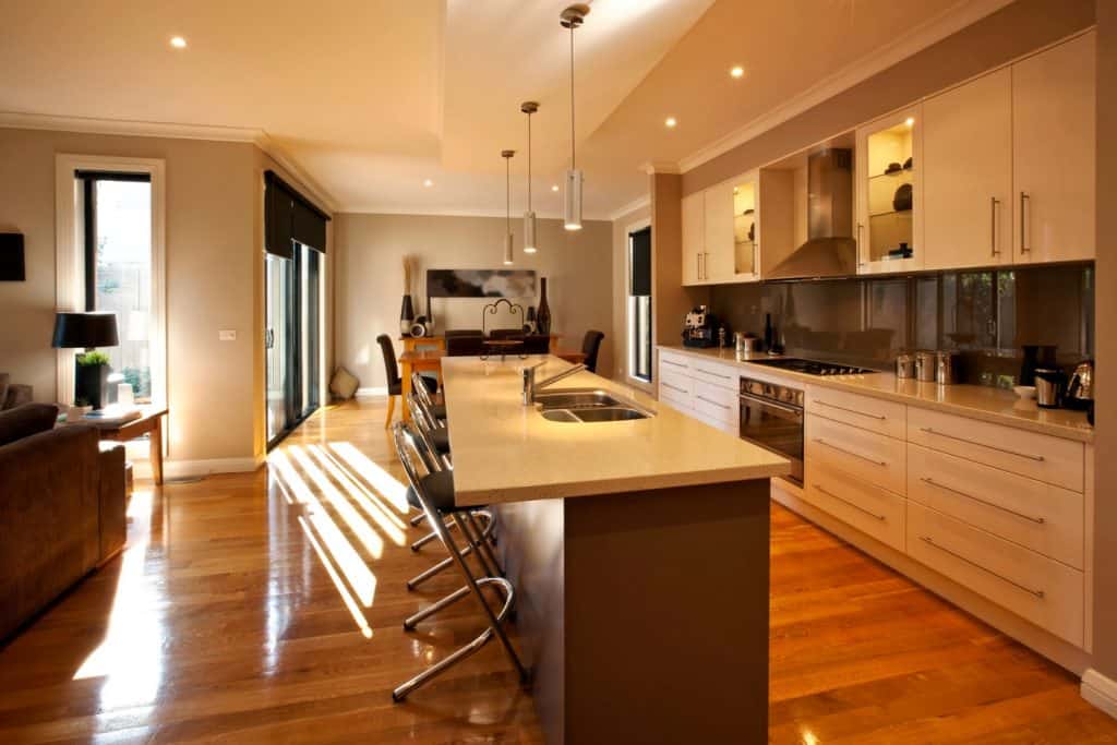 Interior of a luxurious and rustic contemporary kitchen with waxed wooden flooring, wooden cabinetry, and a recessed lighting