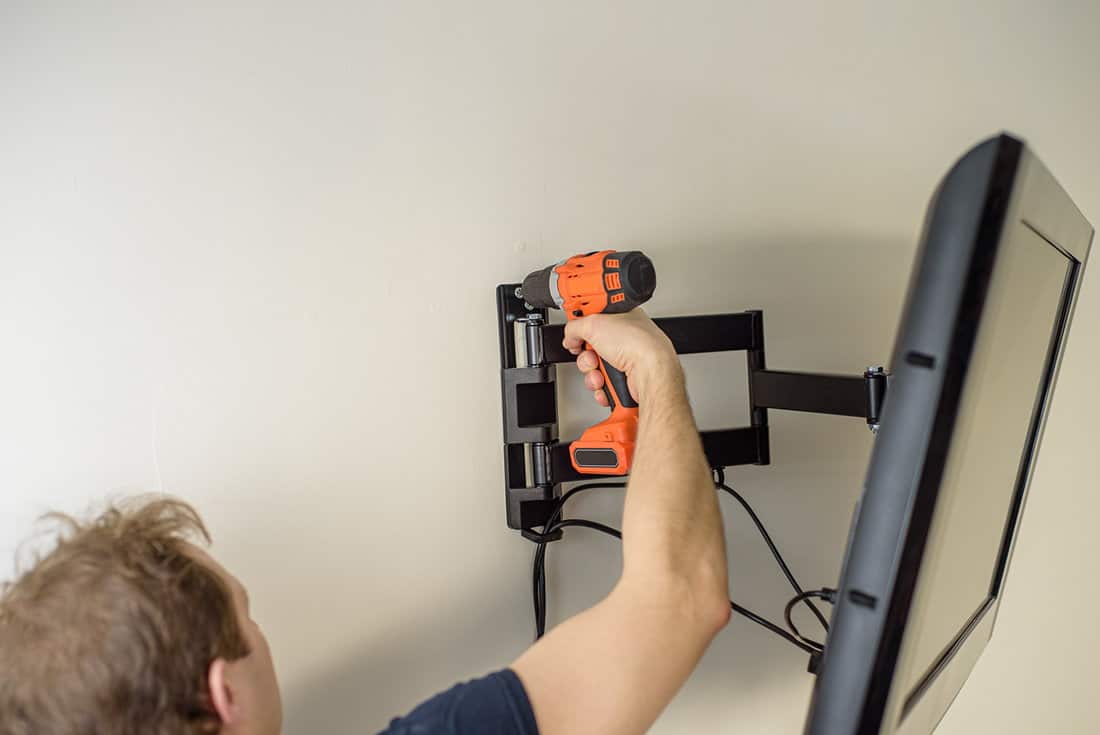 Man hands installing mount TV on the wall
