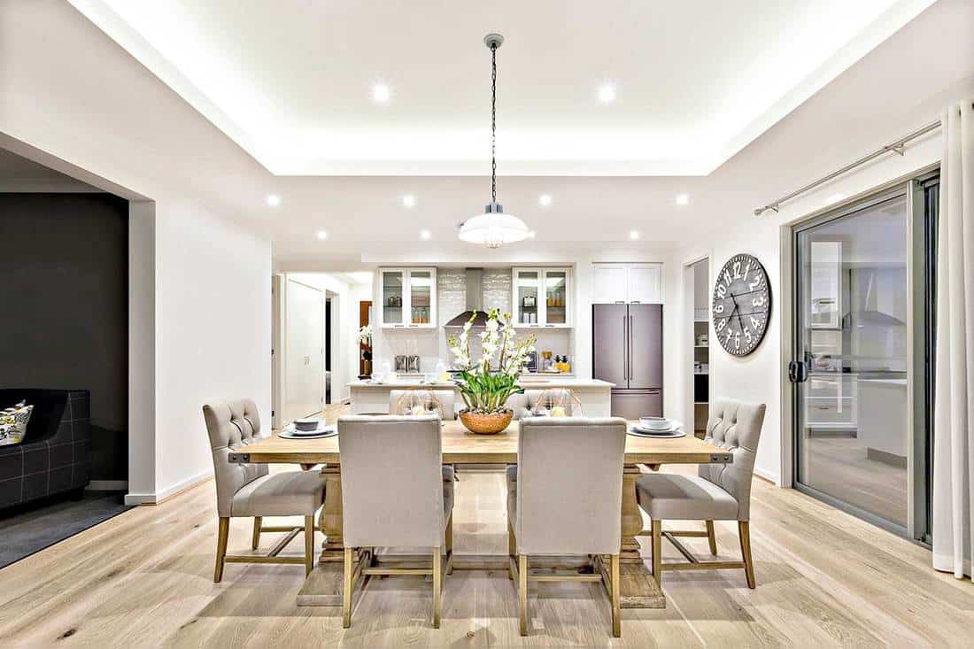 Modern dining room with hanging lamps on, chairs and table setup with fancy items on the wooden floor