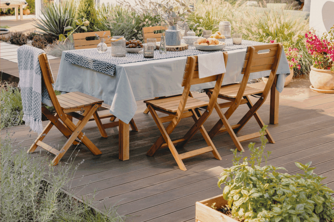 Real photo of a dining table with wooden chairs set on the terrace. How To Keep Tablecloth From Slipping [5 Tips & Tricks]