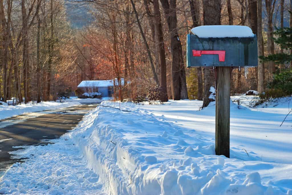 Road covered in snow with a mailbox on the side