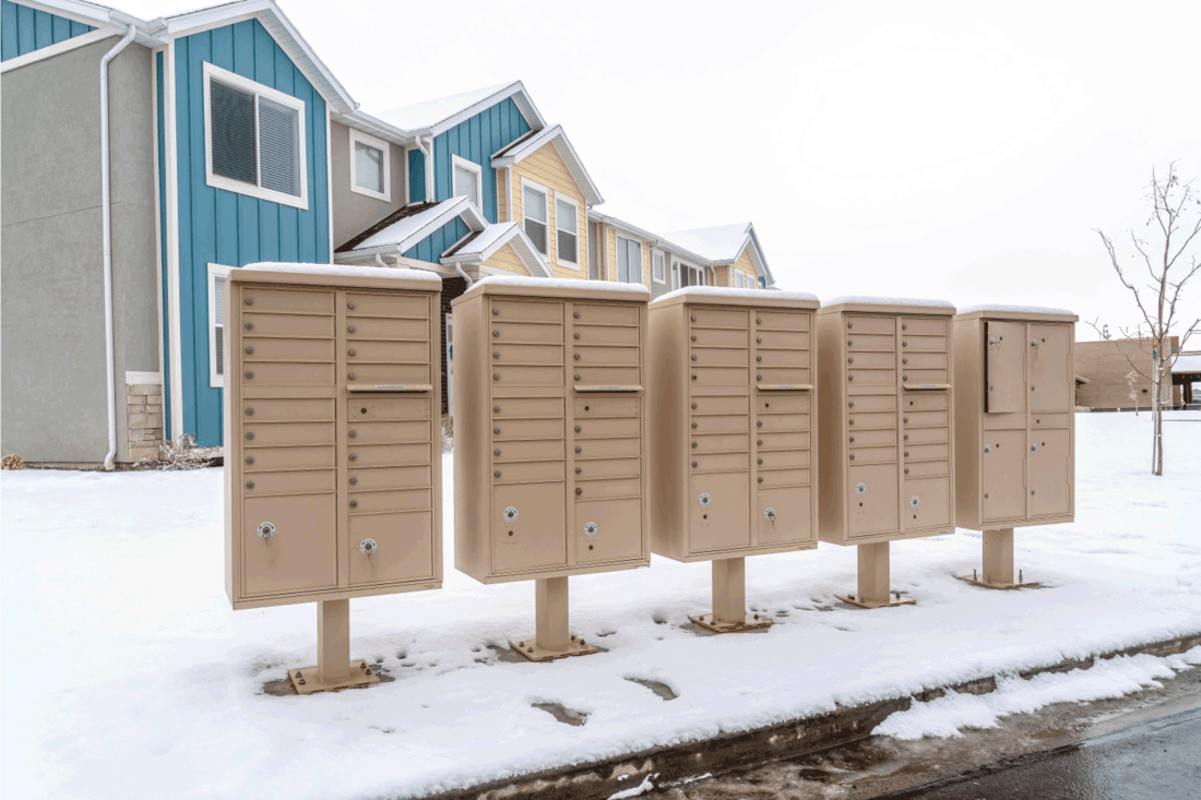 Row of mailboxes on the snowy street along a wet neighborhood road in winter