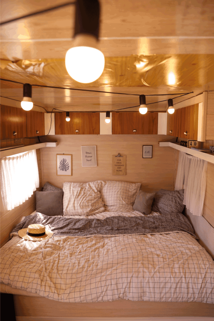 Stylish room interior with comfortable bed and pillows in modern trailer. Camping vacation 