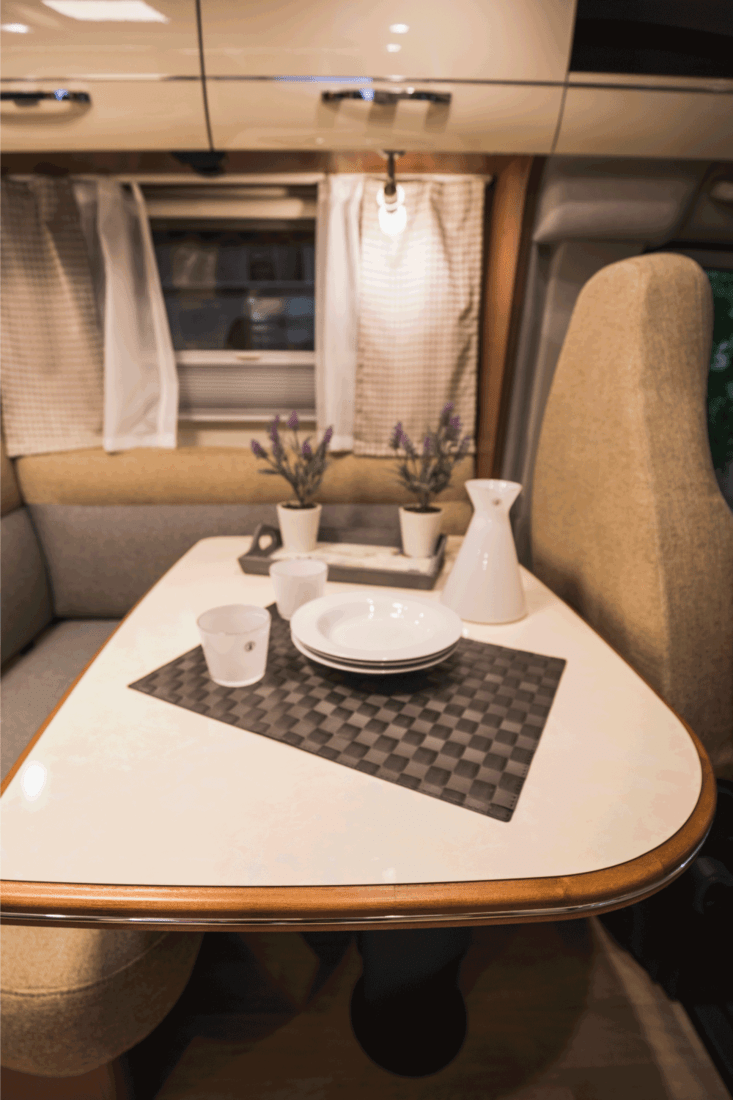 decorative white plates and cups with two flower vases on a table inside a caravan. Travel With Placemats And A Set Of Lovely Non-Breakable Table Ware
