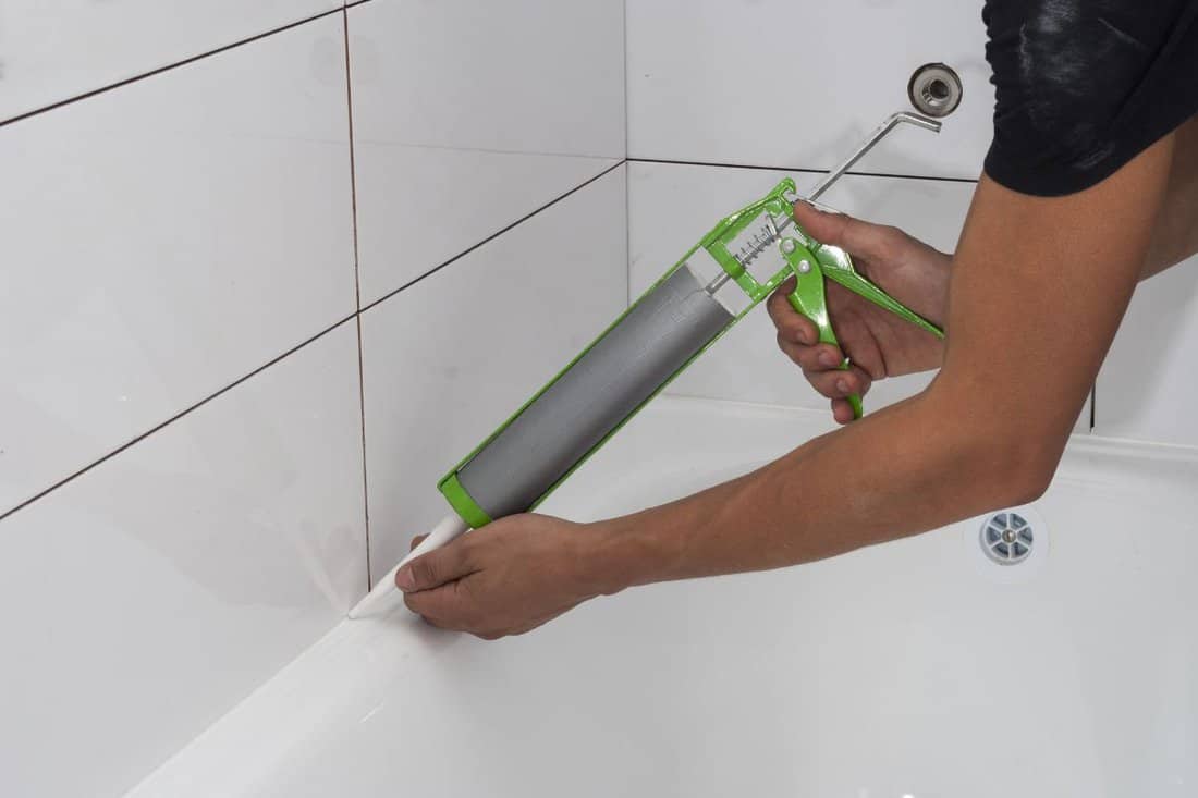 plumber apply silicone sealant to the joint bathtubs and ceramic tile.