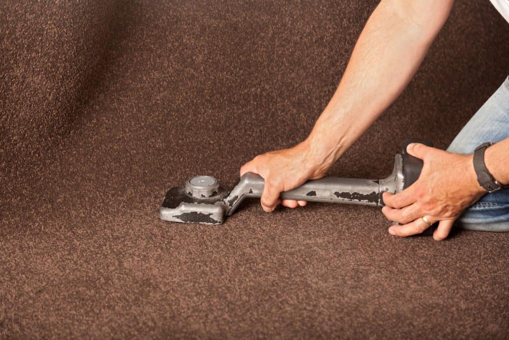 A carpet installer using a knee kicker to properly place the carpet