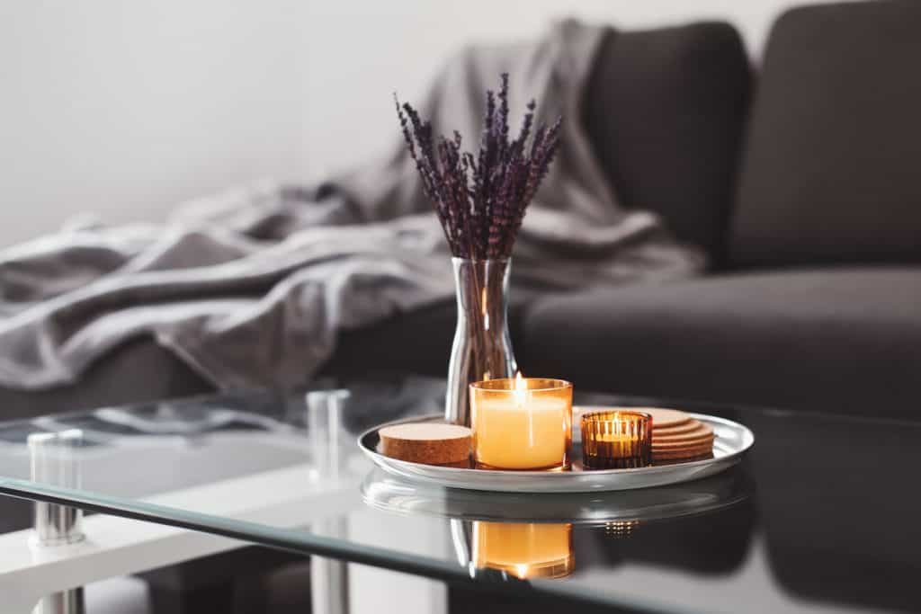 A contemporary home with a long glass coffee table with a candle and cookies 