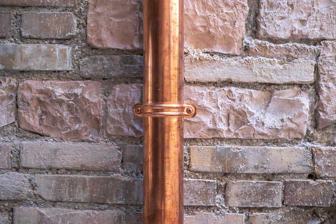 A downspout pipe attached on brick wall