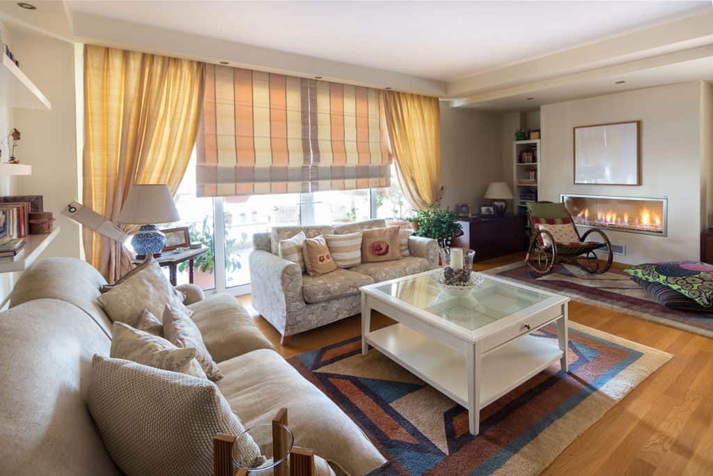 A large living room with beige sofa, white glass coffee table, and wooden flooring