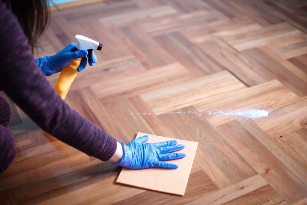 A woman cleaning the parquet flooring using a cltoh