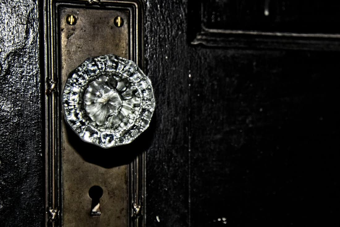 Antique crystal door knob with bass door plate and keyhole for an old fashion skeleton key mounted on a wooden door