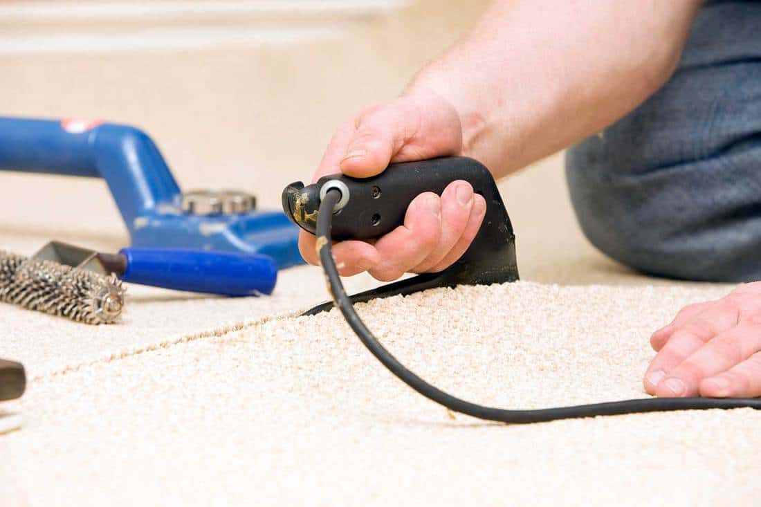Carpet installer joining two pieces with seam iron
