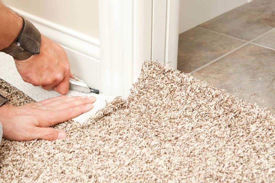 Carpet installer using knife to trim wall edge, How To Install Carpet Over Ceramic Tile
