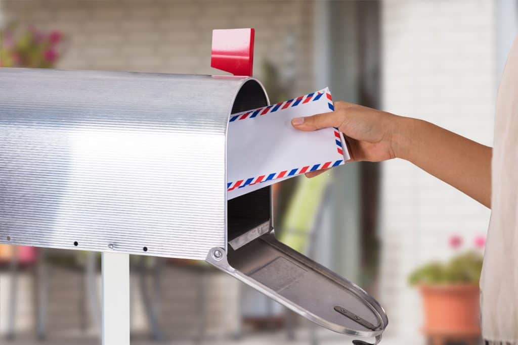 Close-up Of A Person's Hand Removing Letter From Silver Mailbox