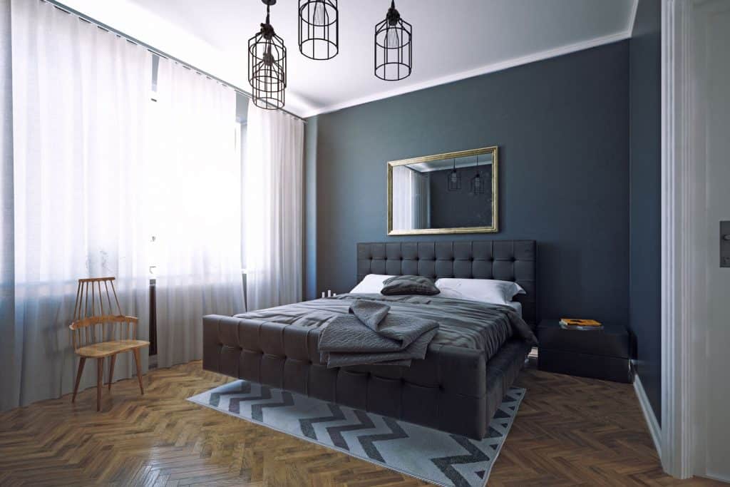 Contemporary interior bedroom with dark blue colored walls, white curtains, and a blue bed