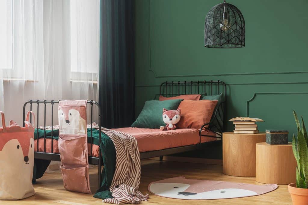 Green inspired bedroom wall with round wooden nightstands and an eclectic inspired bed