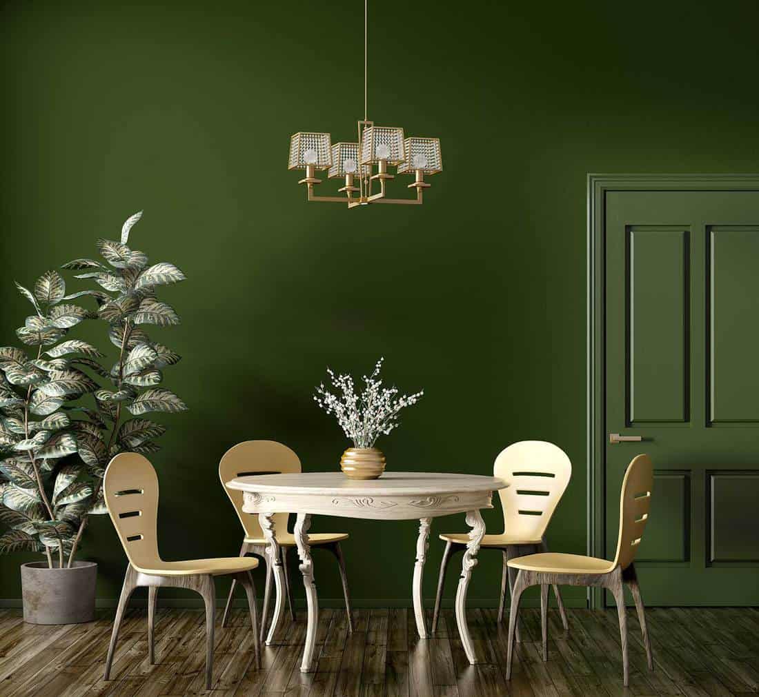 Interior of modern dining room with wooden classic table and yellow chairs against dark green wall with door
