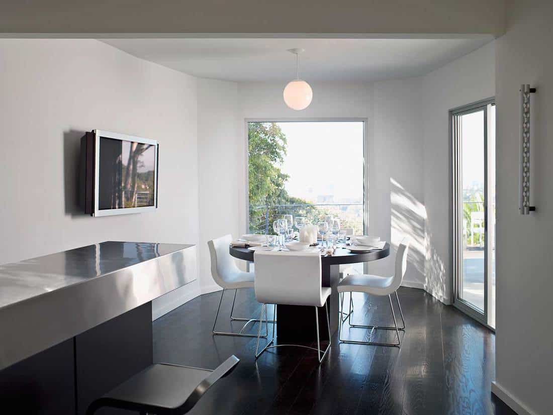 Interior of modern dining room with wall mounted TV on white walls