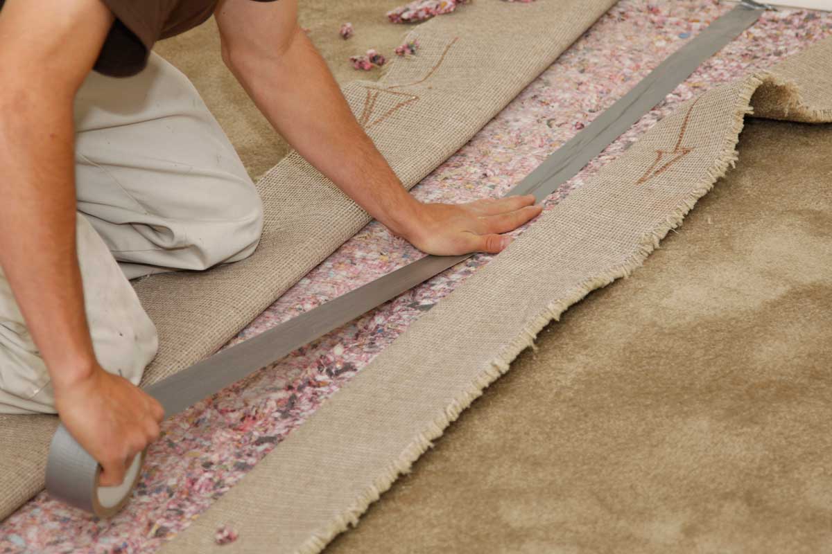 Man installing new carpet, How To Use Seam Tape On Carpet