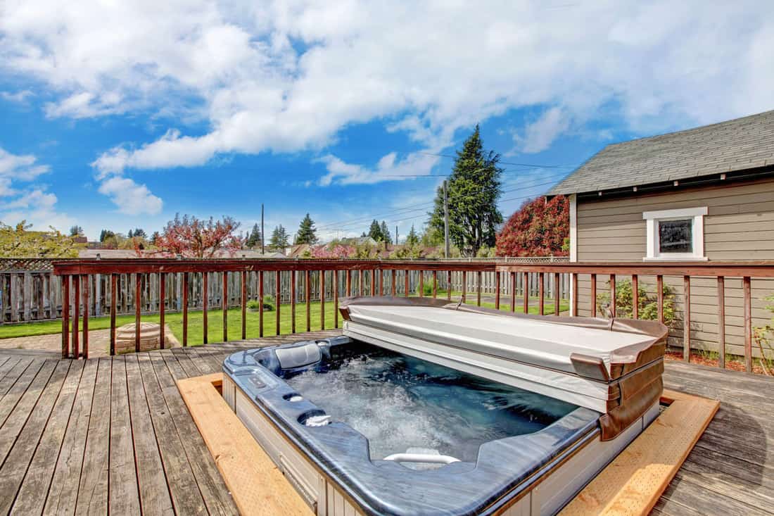 Modern jacuzzi on the backyard of a house with a gorgeous scenic skyline view, How Often Should You Clean A Jacuzzi Tub?