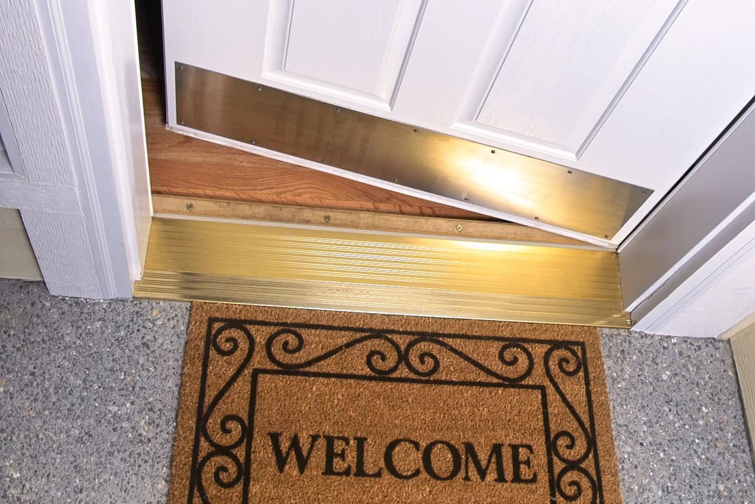 Photo of a welcome mat in front of a white door of a modern home with transition strips, 