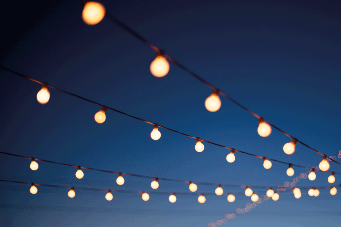 String lights hang outdoors on a summer evening.