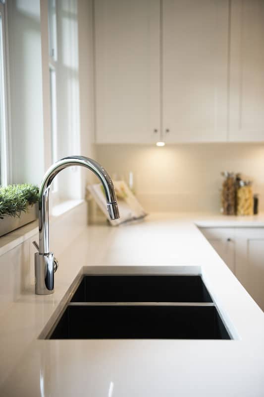 White countertop, black sink, and a recessed lighting on the back