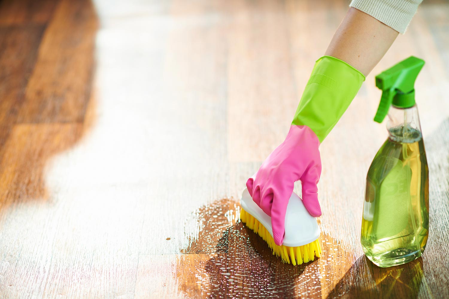 Woman with cleaning agent and brush wet cleaning floor
