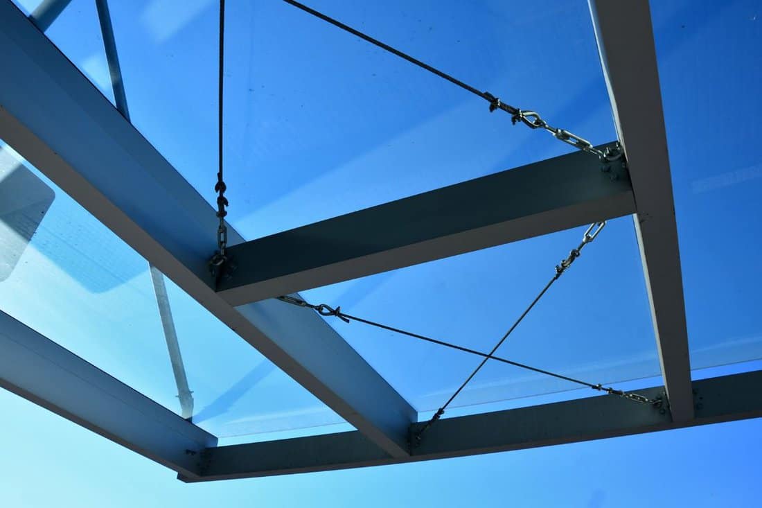 strut, suspended glass roof above the building entrance. bus station, railway station. cable wind braces. aluminum construction with windows above the pergola.