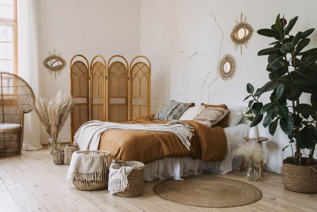 A bohemian styled bedroom decorated with wooden furnitures and brown rustic baskets and blankets