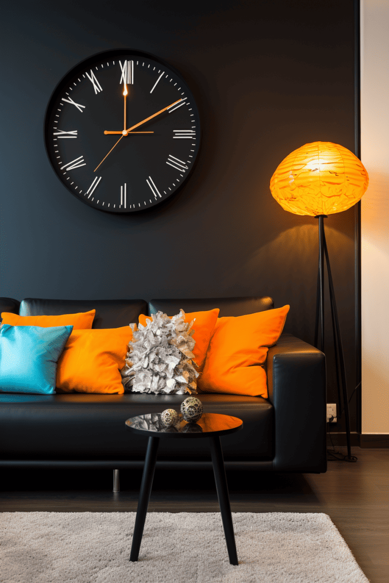 A contemporary black living room with a black couch, vibrant pops of color, a simple pole lamp, and a big contemporary clock on the wall