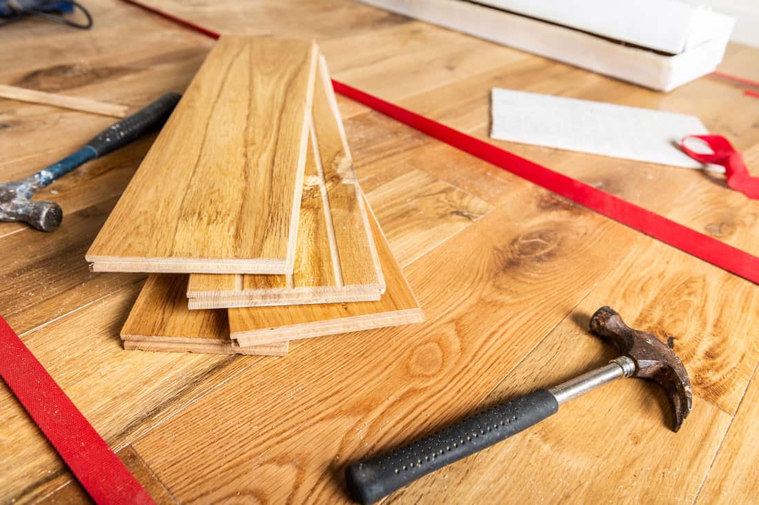 A floorboard being installed in the living room, How To Fix A Cracked Floorboard