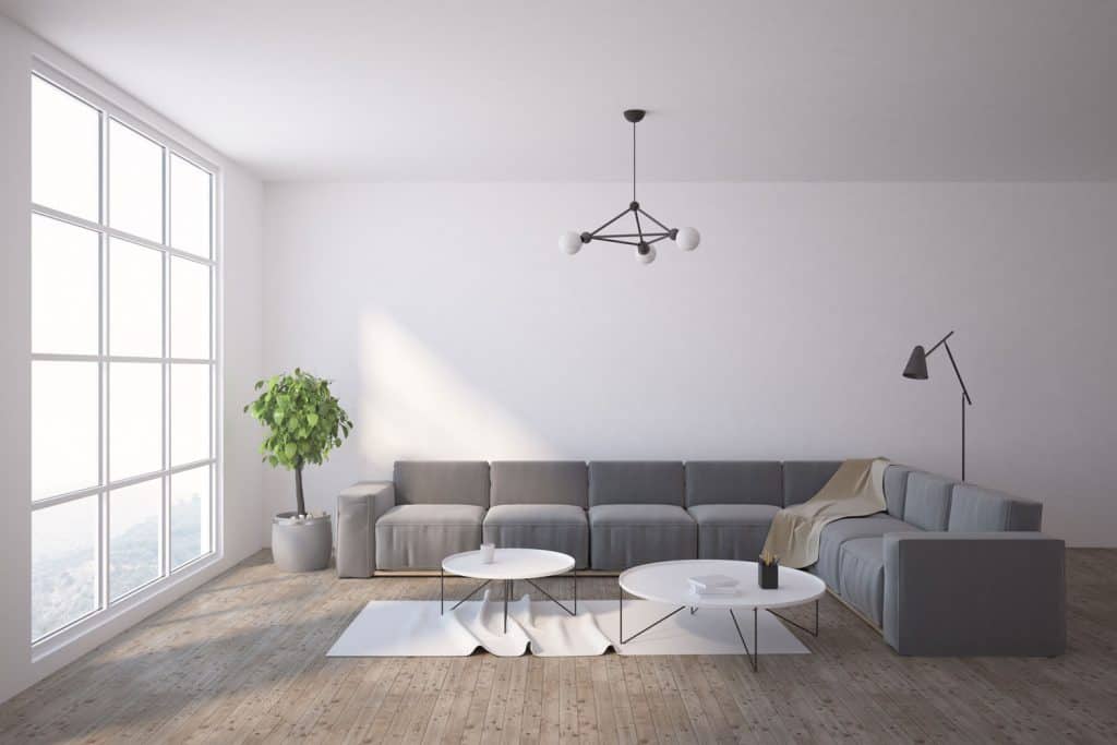A gray sectional sofa inside a living room with laminated flooring